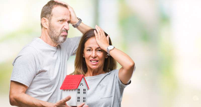 Middle age hispanic casual couple buying new house over isolated background stressed with hand on head, shocked with shame and surprise face, angry and frustrated. Fear and upset for mistake.